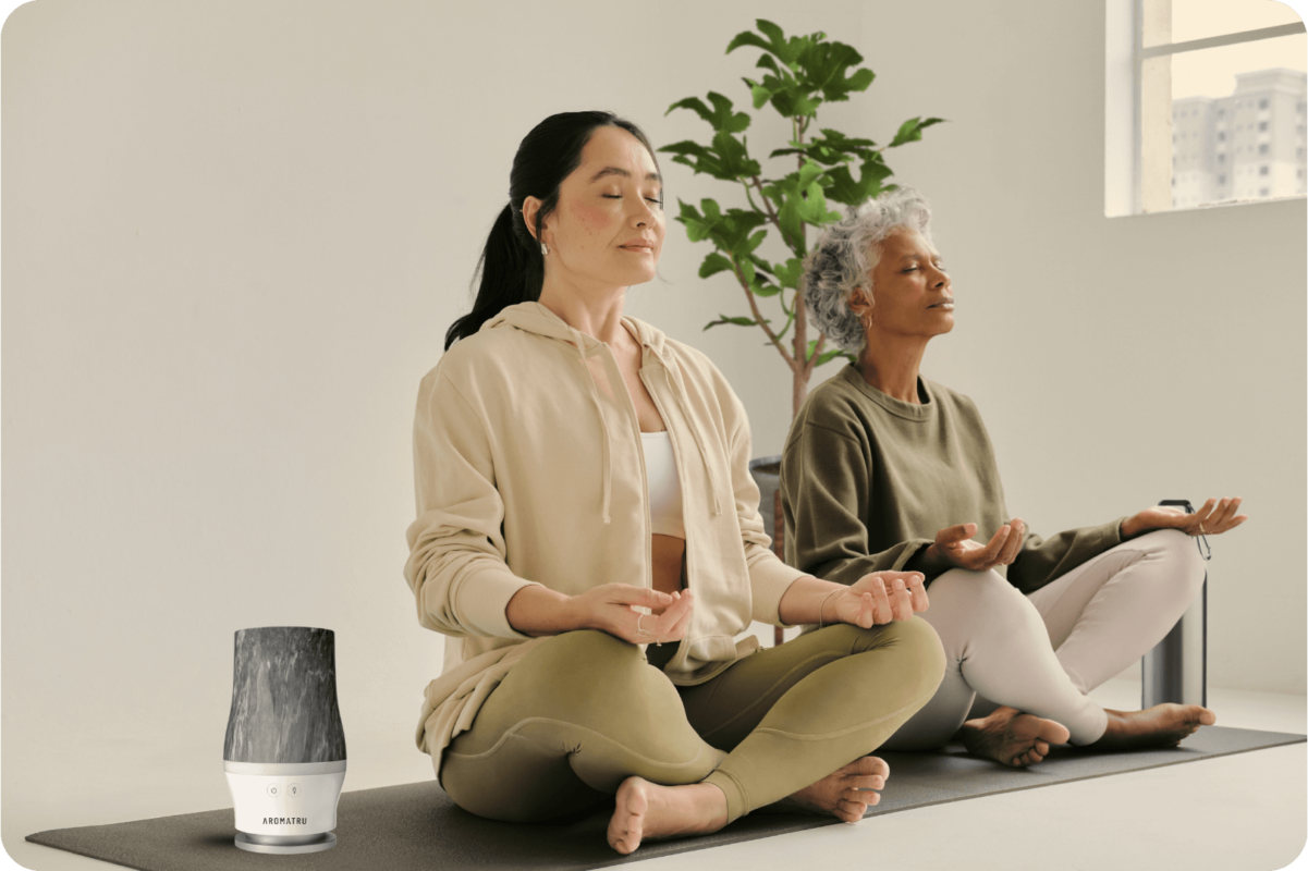 2 women meditating next to an AromaTru diffuser
