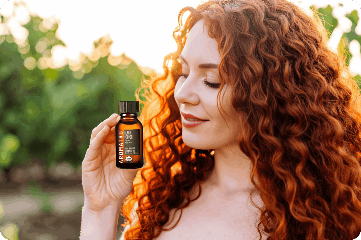 Lady holding black pepper essential oil